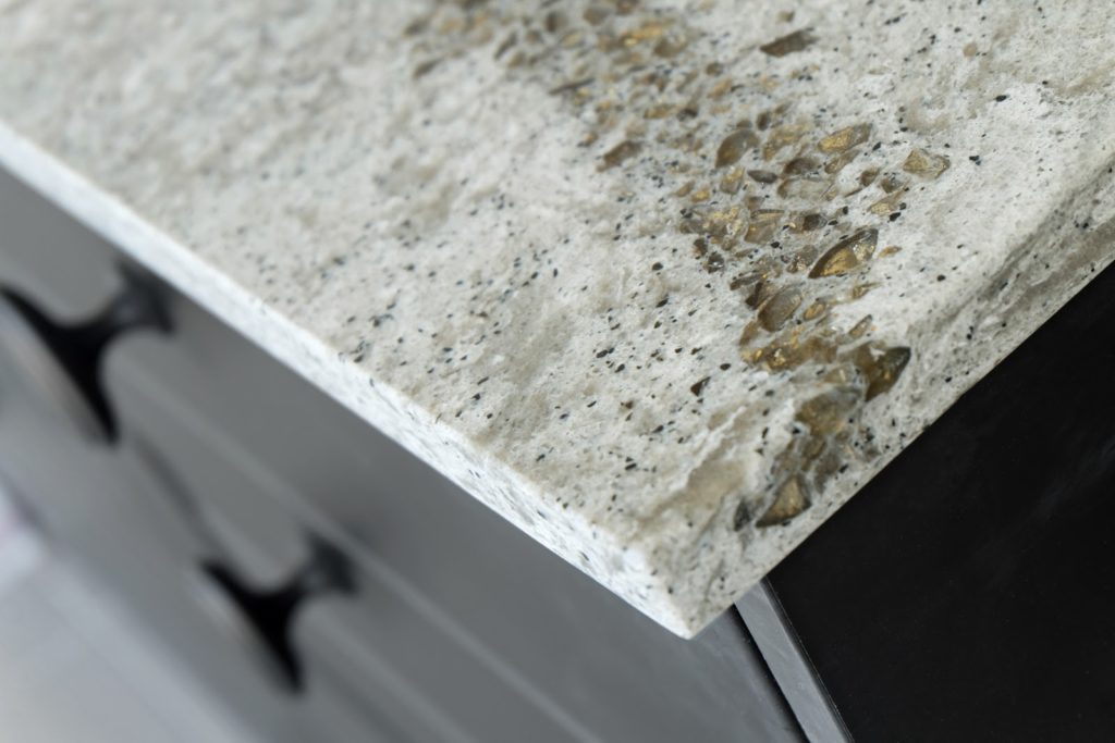 Corner of a speckled stone countertop and black cabinet